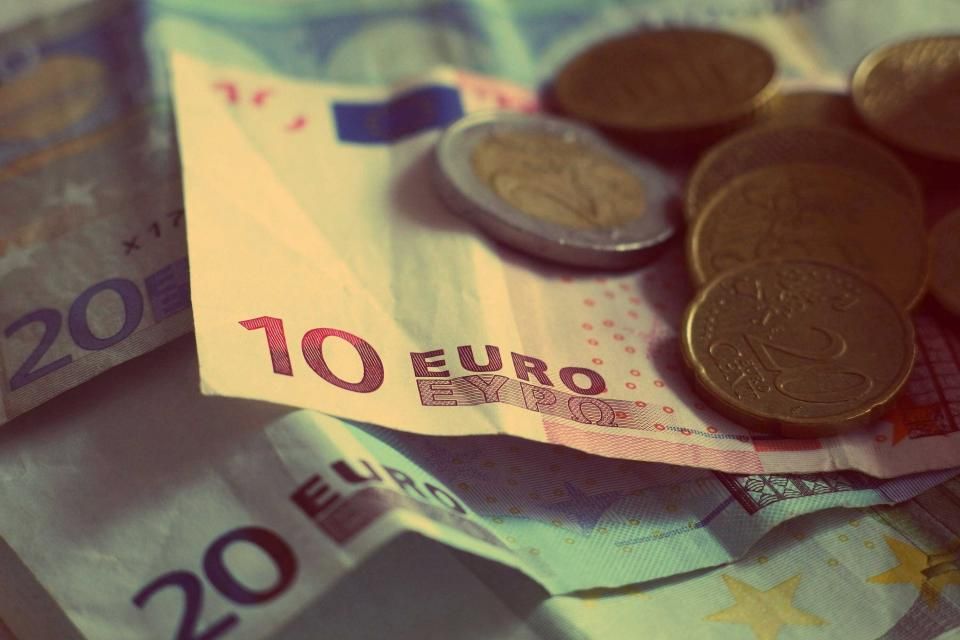 Euro banknotes and coins fanned out on a table