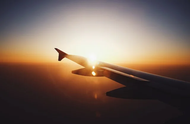 Silhouette of an airplane wing against a sunset sky, symbolizing day and night across time zones